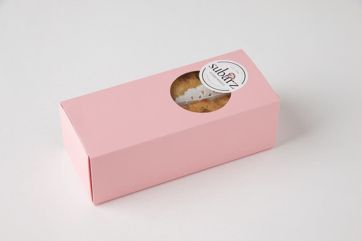 Elegant pink box containing eight gluten-free spiced fig Subarz, with a window displaying the golden baked treats and lace paper accents. The signature Subarz Home Baked logo adorns the top of the premium gift packaging, photographed against a clean white background.