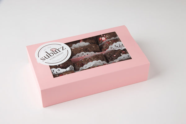A lovely pink box, gracefully presenting two dozen Chocolate Peppermint Subarz, each artfully wrapped in a delicate doily. These delightful treats feature the harmonious blend of rich chocolate and refreshing peppermint, garnished with vibrant crushed peppermint candies. Perfect for sharing or elegant gifting